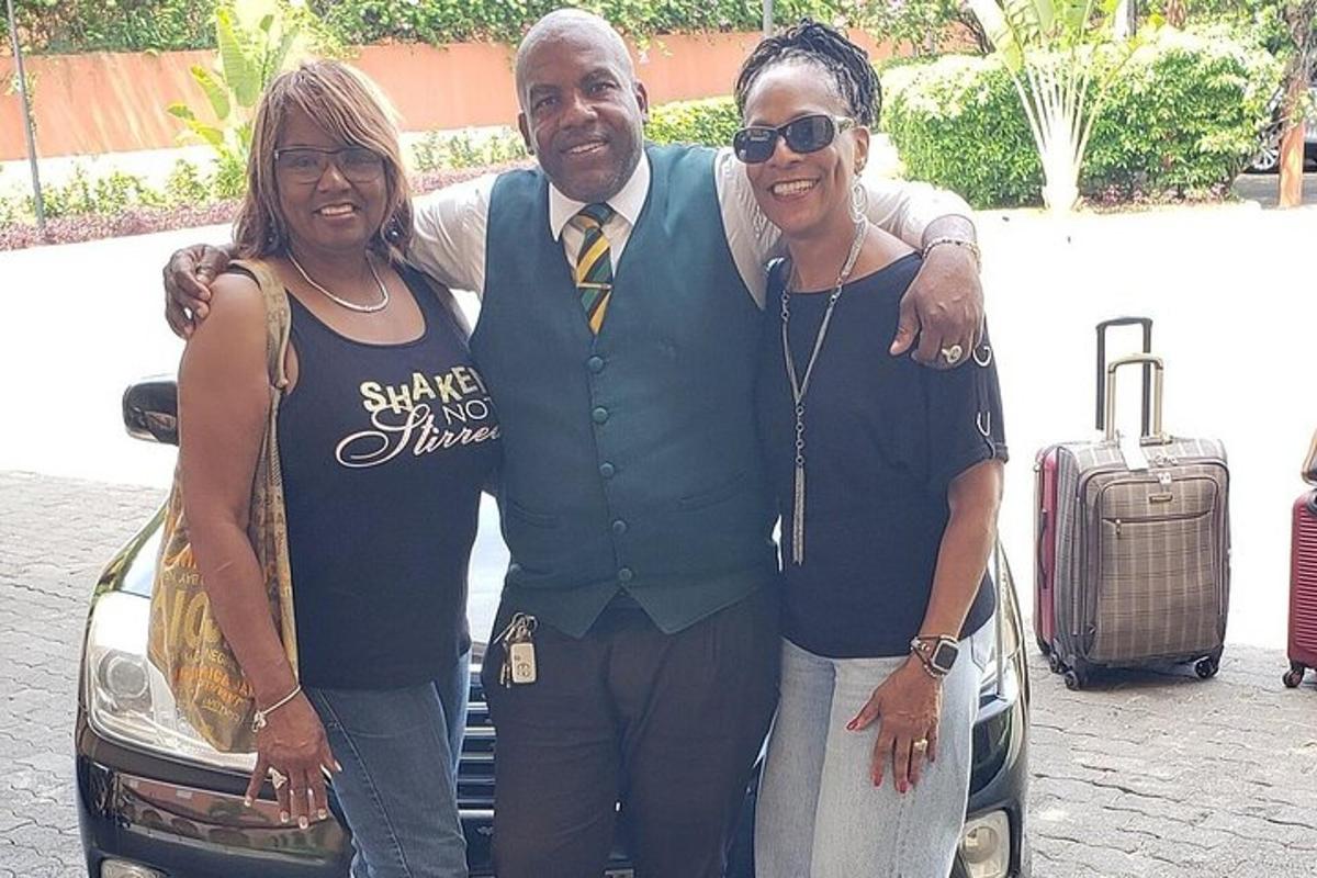 Un hombre y dos mujeres de pie junto a un coche.