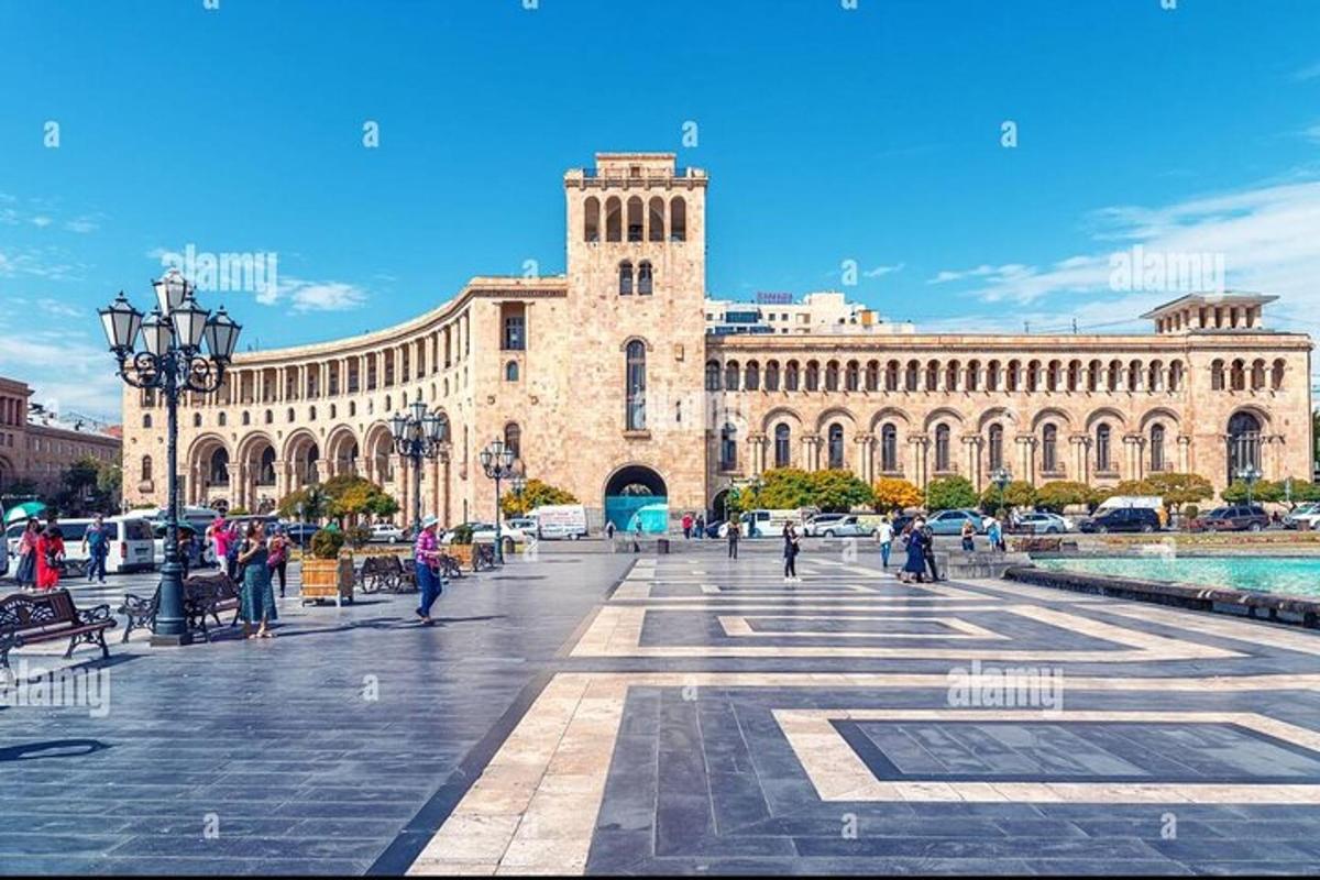 Un gran edificio con una torre de reloj en una plaza.