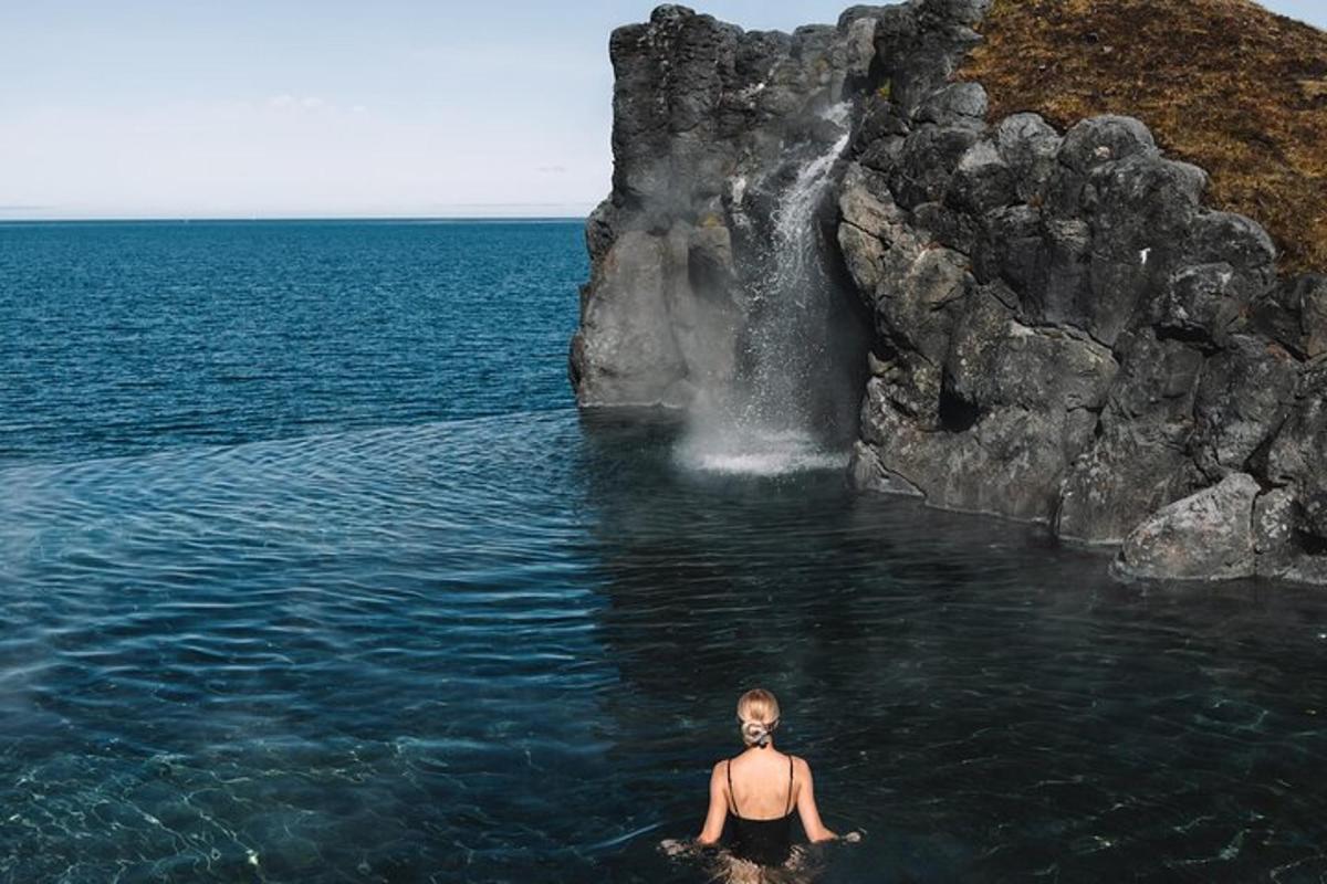 maður í vatninu fyrir framan foss