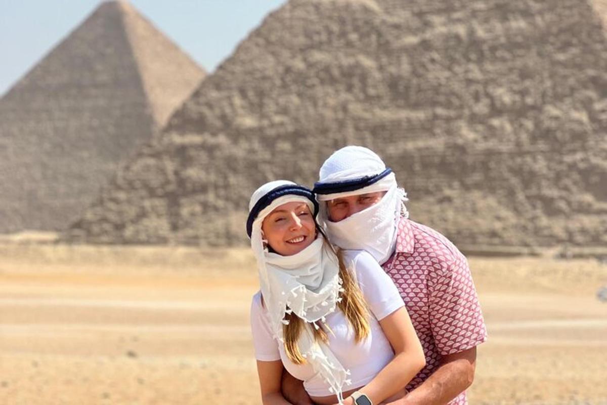 Un hombre y una mujer de pie frente a las pirámides.