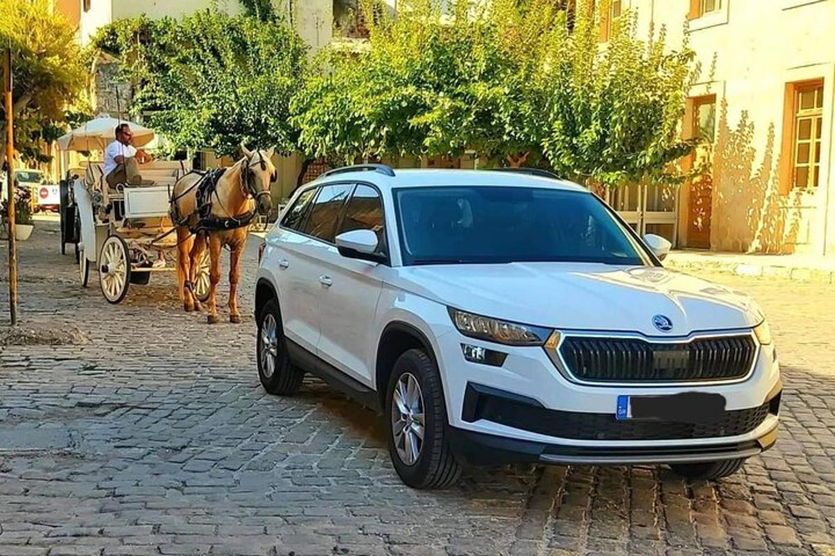 Una camioneta blanca estacionada en una calle con un carruaje tirado por caballos