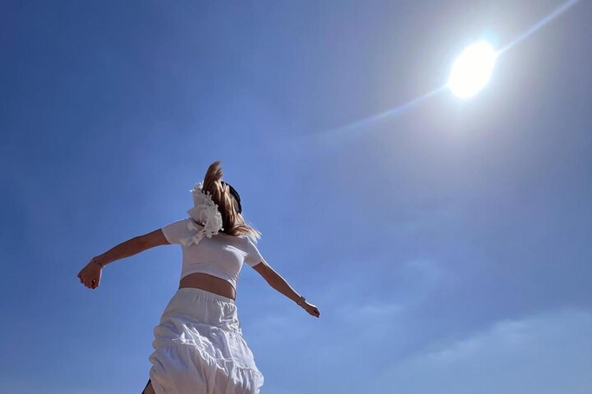 Una mujer saltando en el cielo con los brazos extendidos.