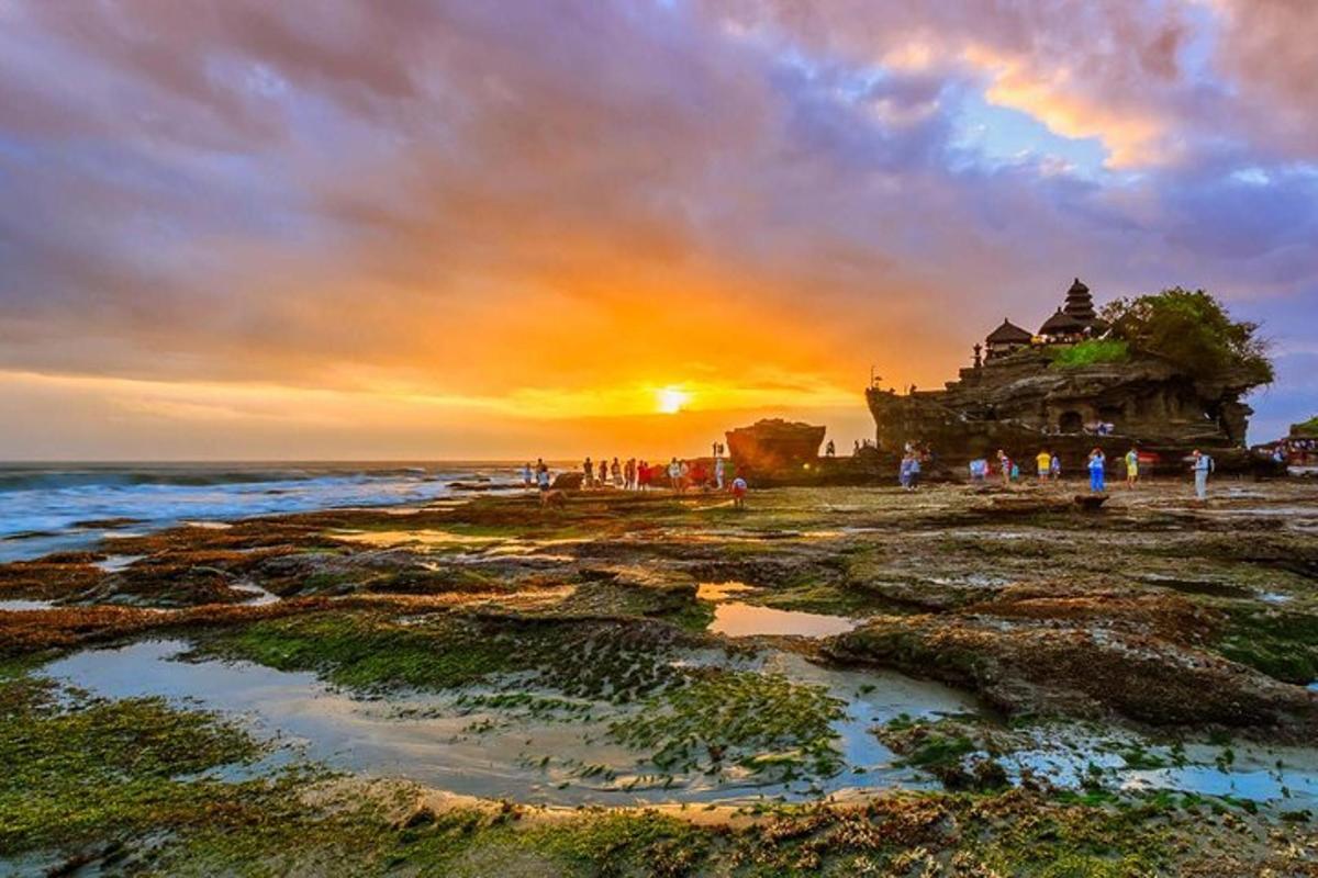 un gruppo di persone in piedi su una spiaggia al tramonto