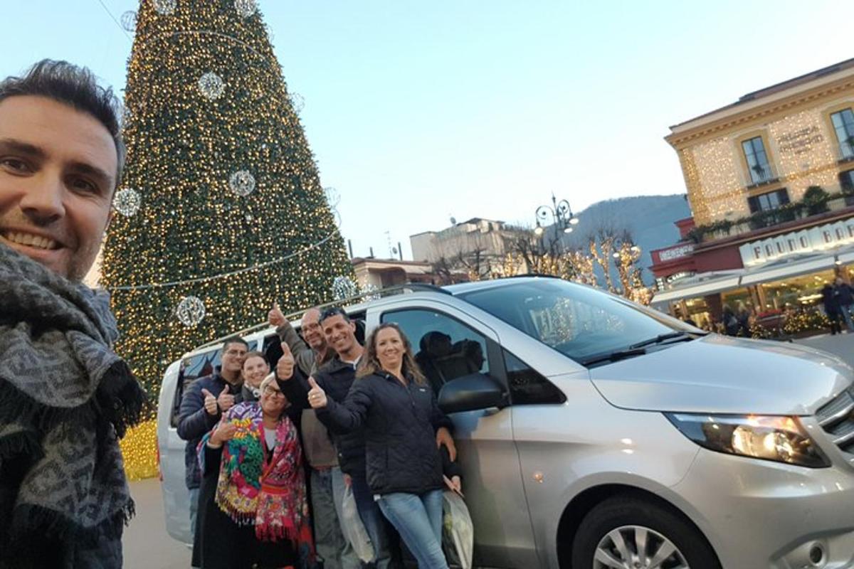 a group of people standing next to a car next to a christmas tree