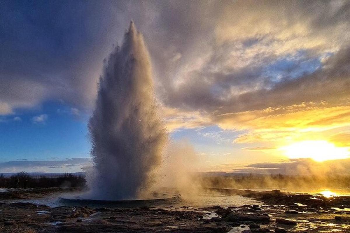un geyser in mezzo a un campo con un tramonto
