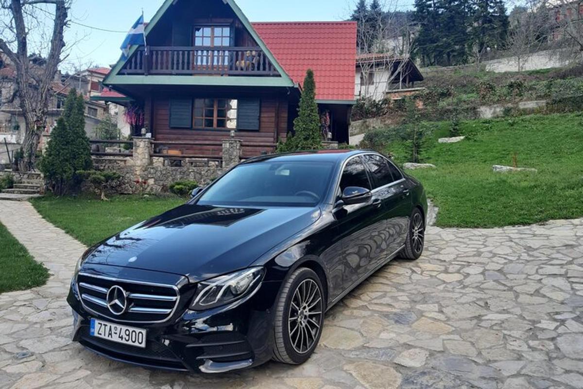 um carro Mercedes Benz preto estacionado em frente a uma casa