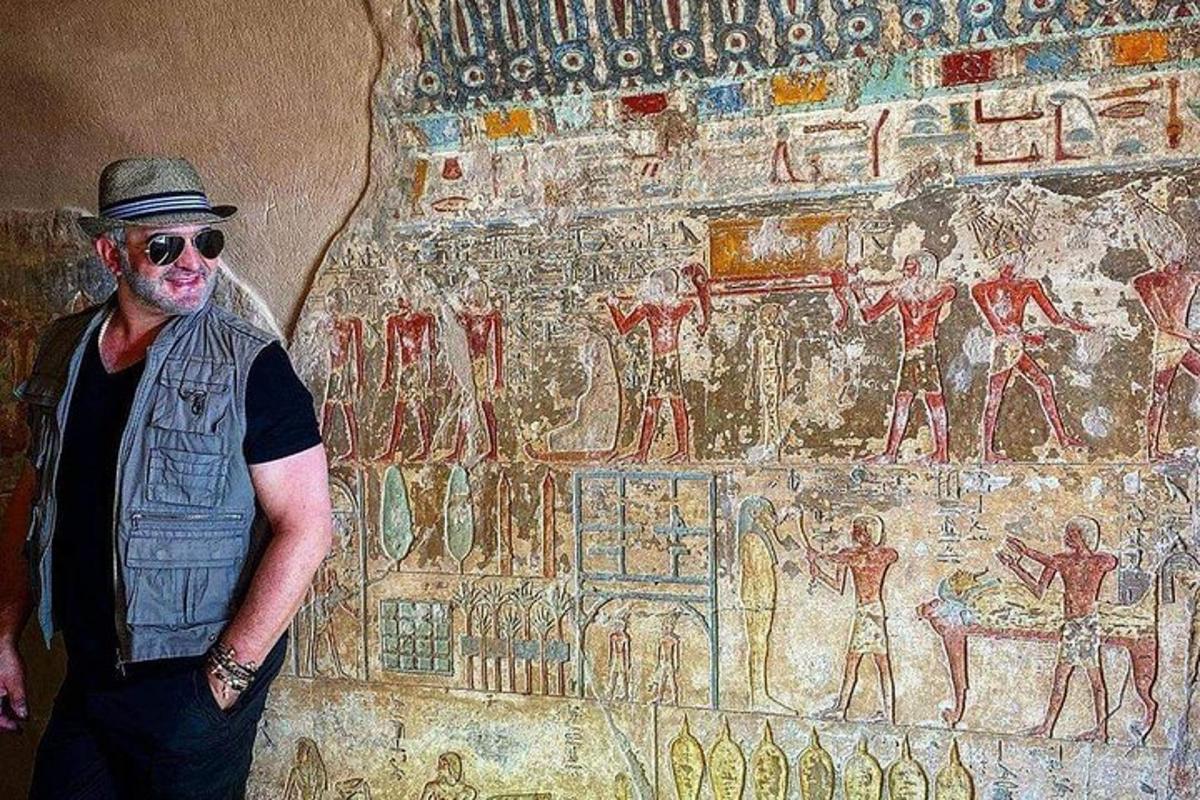 Un hombre parado frente a una pared con un mural.