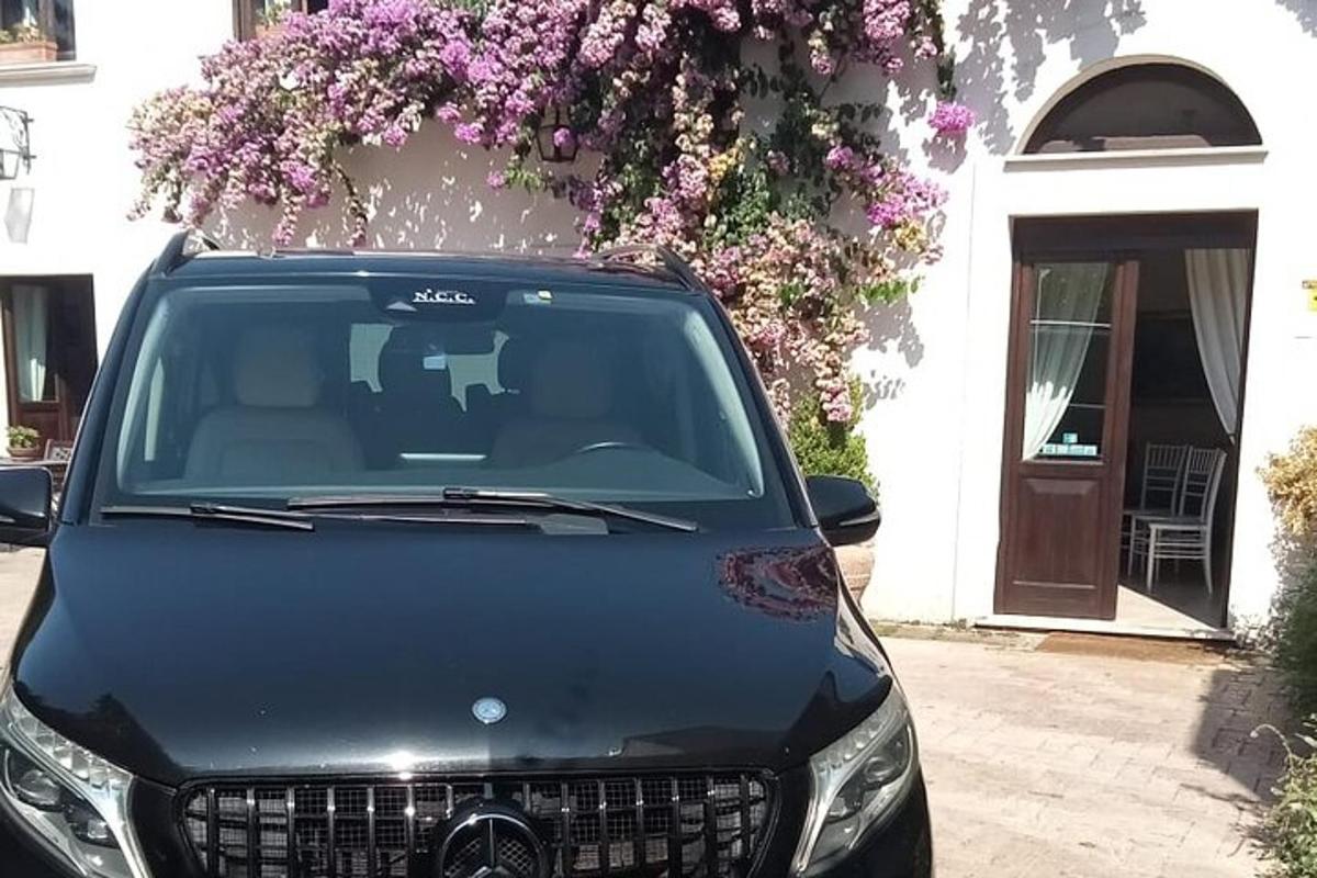 juodas automobilis, pastatytas priešais namą su gėlėmis