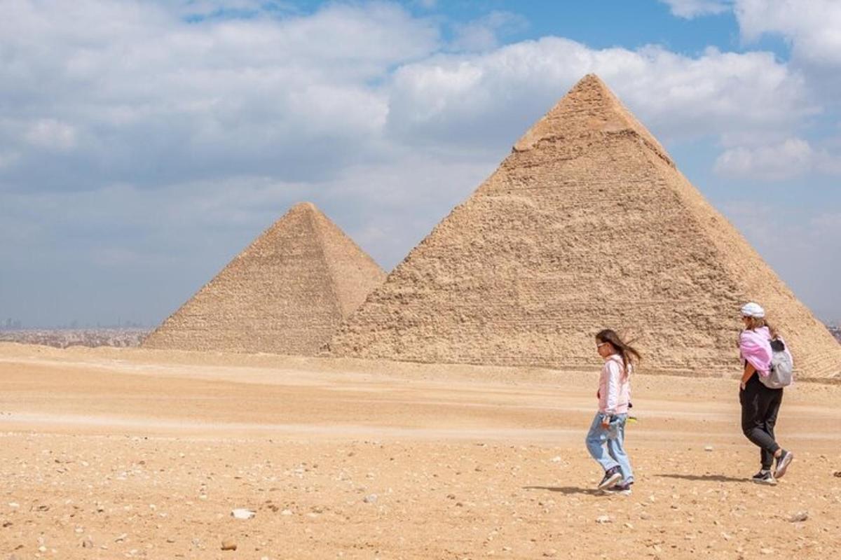 dva lidé jdoucí před pyramidami