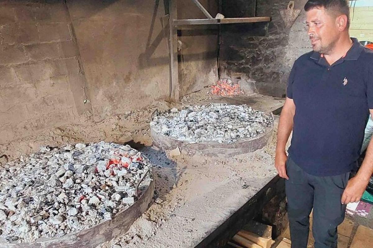 un uomo in piedi davanti a una griglia con due padelle