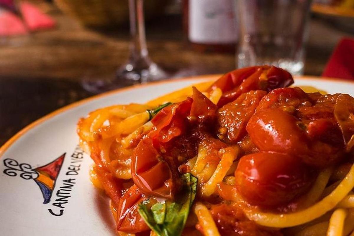 a plate of food with pasta and tomatoes on a table