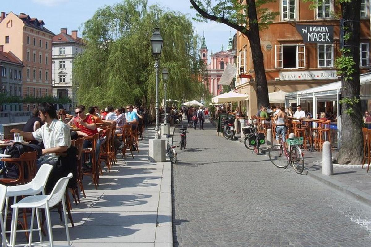 uma rua com mesas e cadeiras e pessoas sentadas às mesas