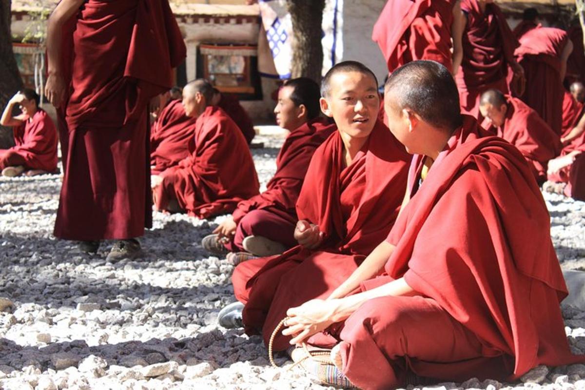 a group of monks in red uniforms sitting on the ground
