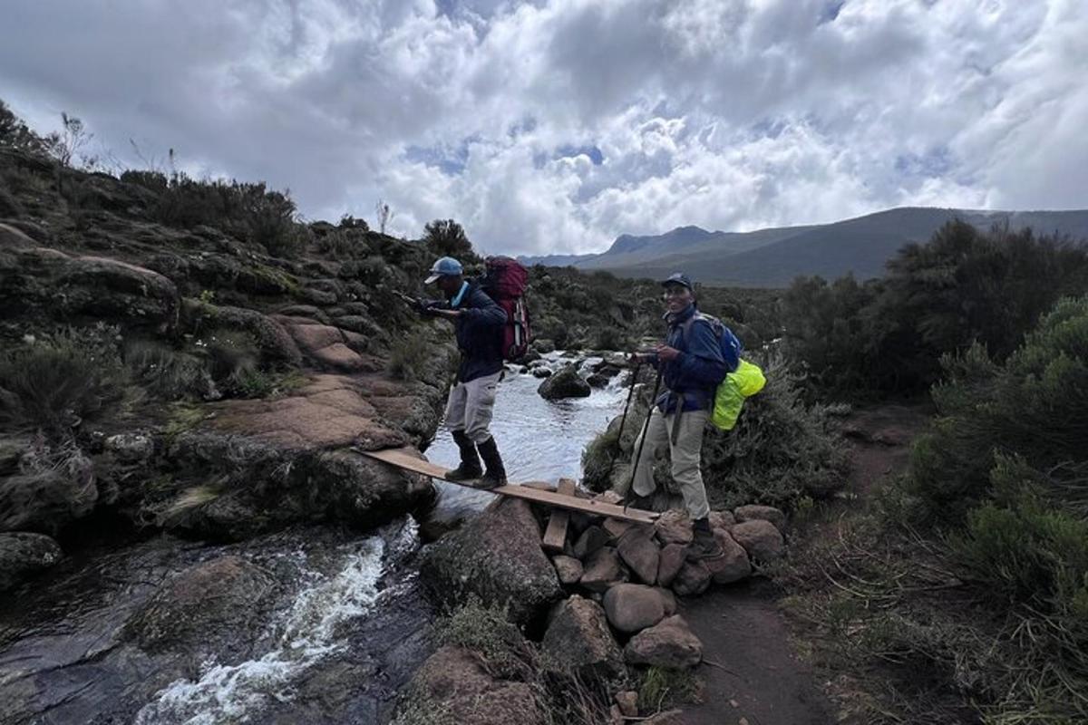 tre persone che attraversano un ponte di legno sopra un fiume