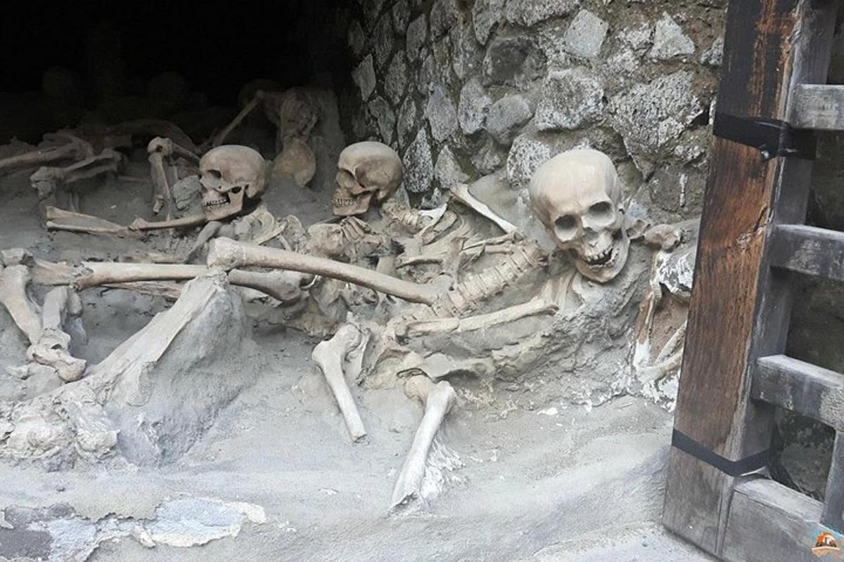 uma pilha de esqueletos deitados no chão em uma caverna