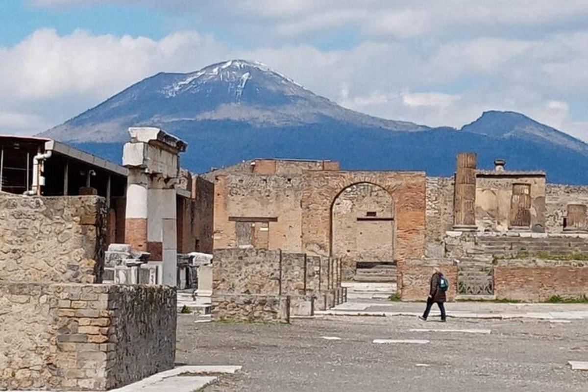 um homem caminhando em frente a um prédio com uma montanha ao fundo