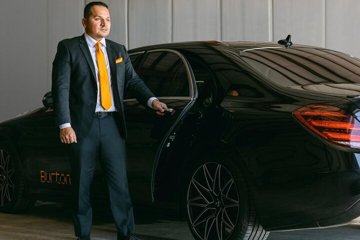 um homem de terno e gravata parado ao lado de um carro