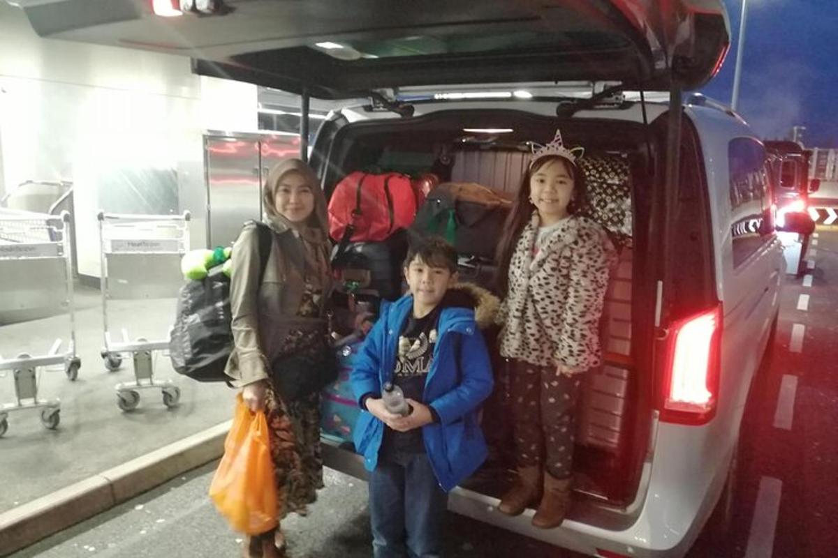 tre bambini sono in piedi sul retro di un furgone
