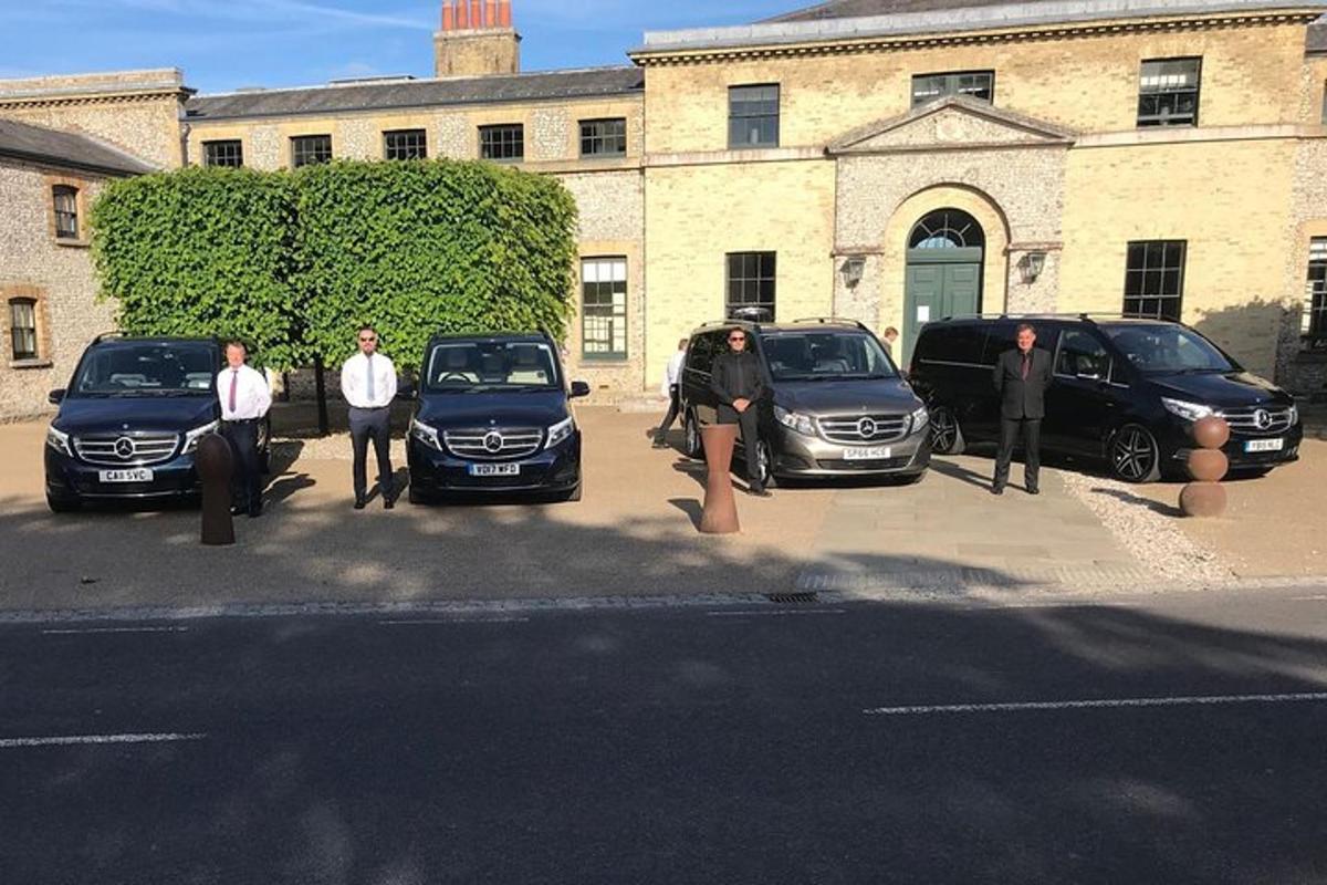 Un grupo de personas paradas frente a autos estacionados.