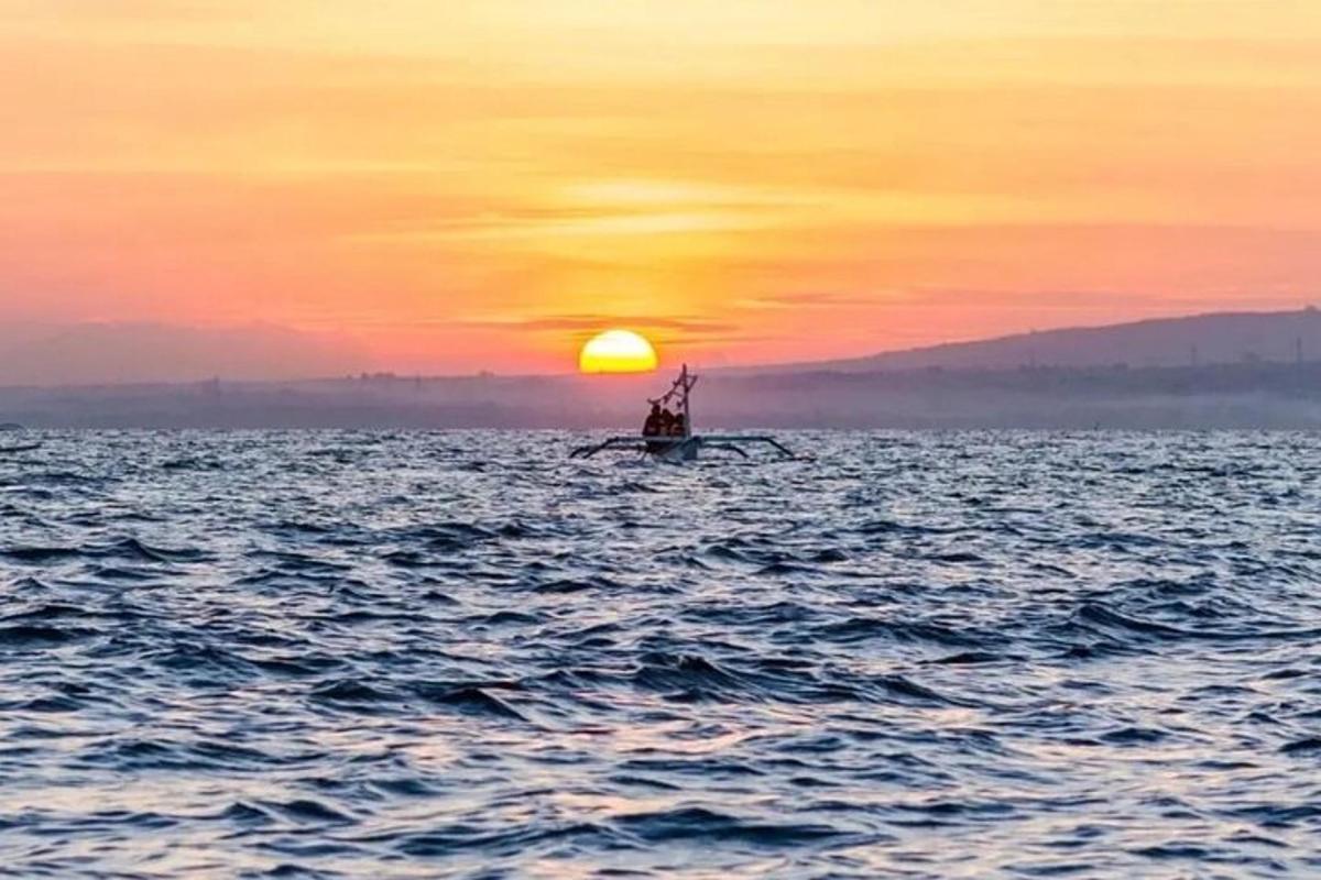 μια βάρκα στον ωκεανό με ένα ηλιοβασίλεμα
