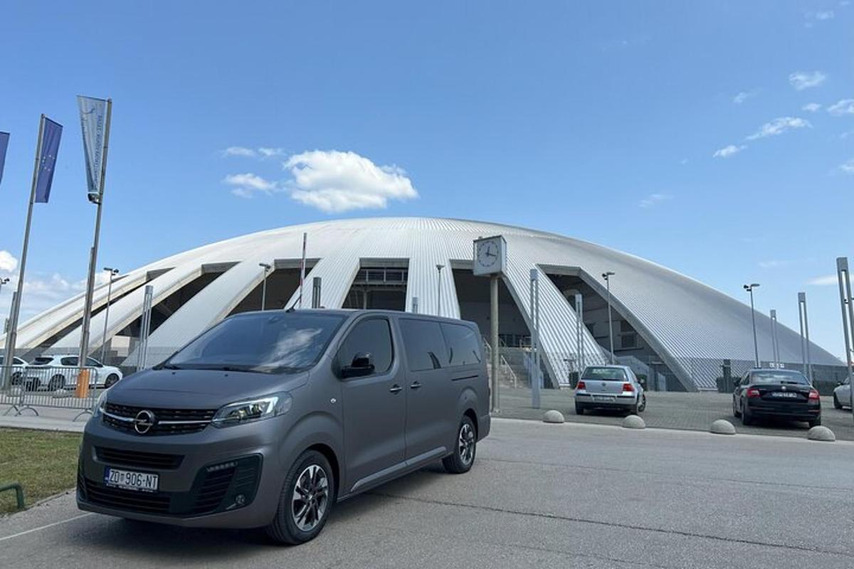 uma van prateada estacionada em frente a um grande prédio
