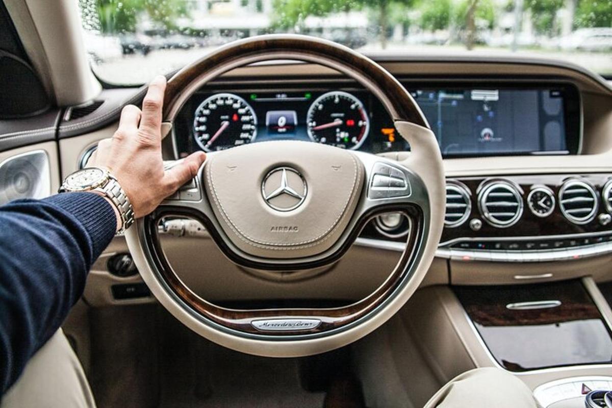 muž šoférujúci auto s rukou na volante