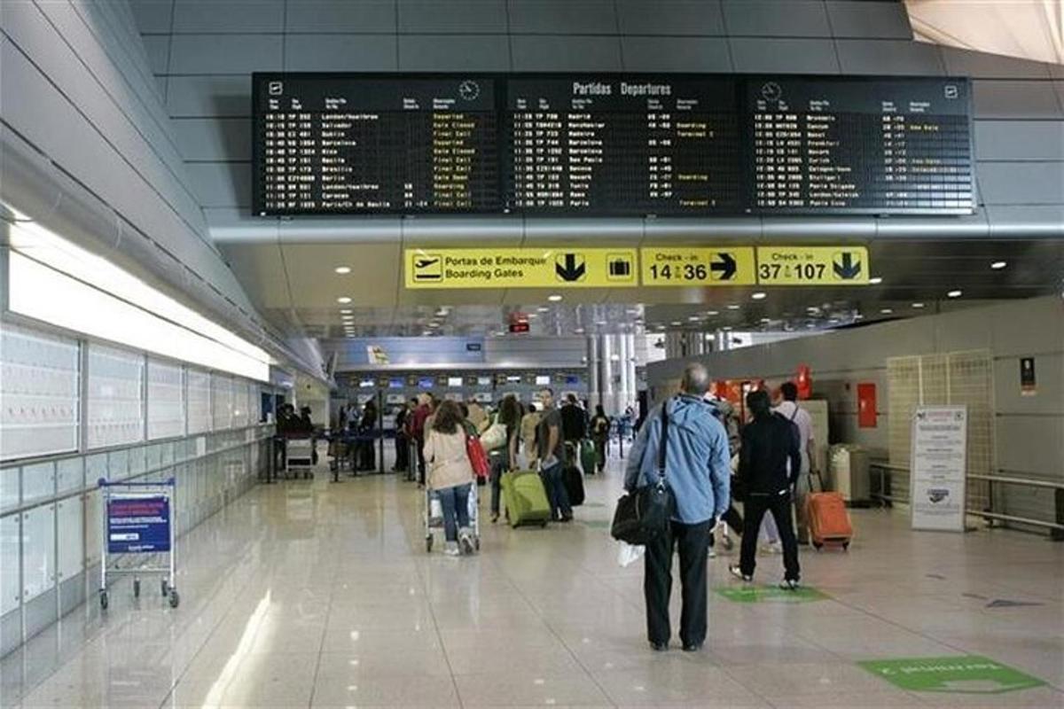 Un grupo de personas caminando por una terminal del aeropuerto.