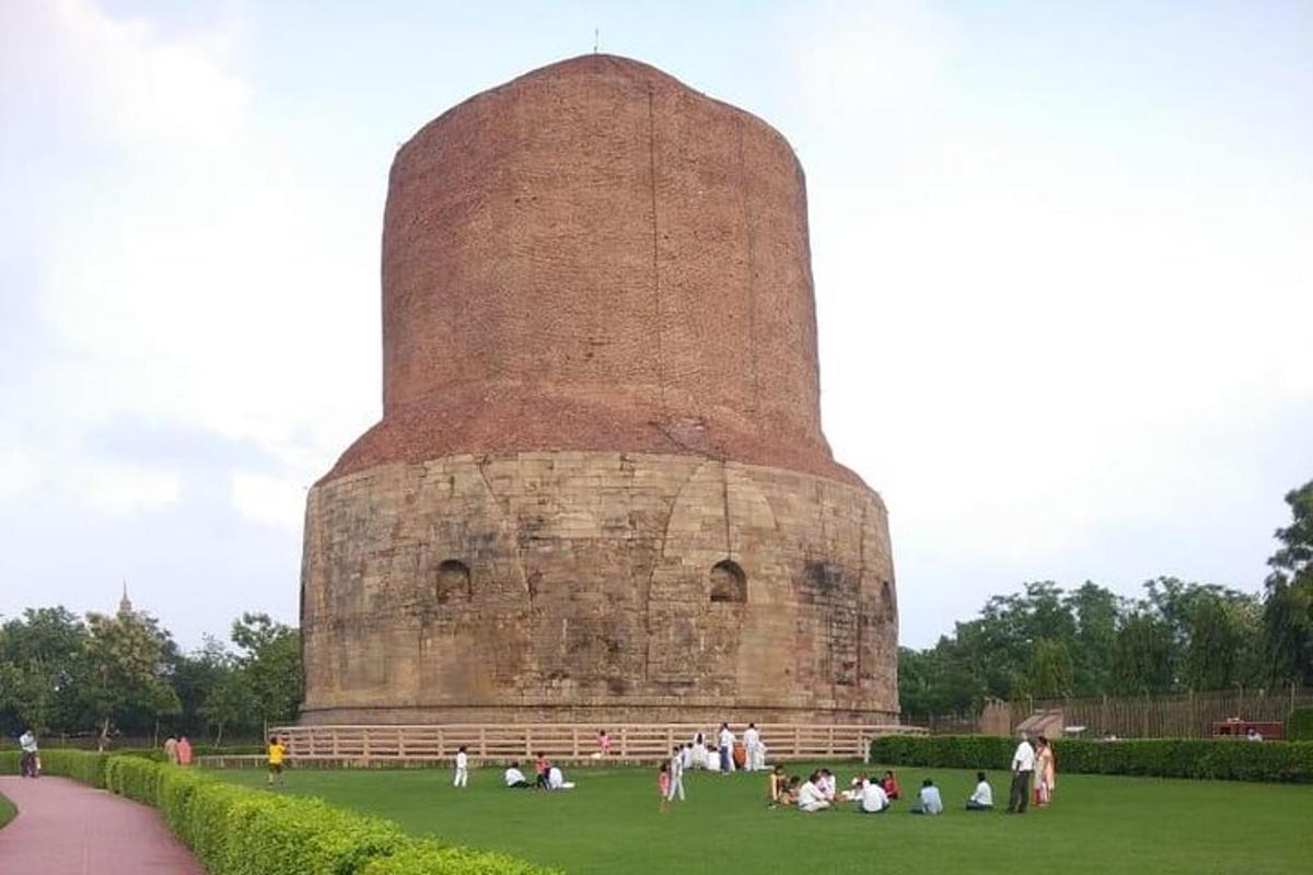 un gruppo di persone sedute sull'erba davanti a una torre