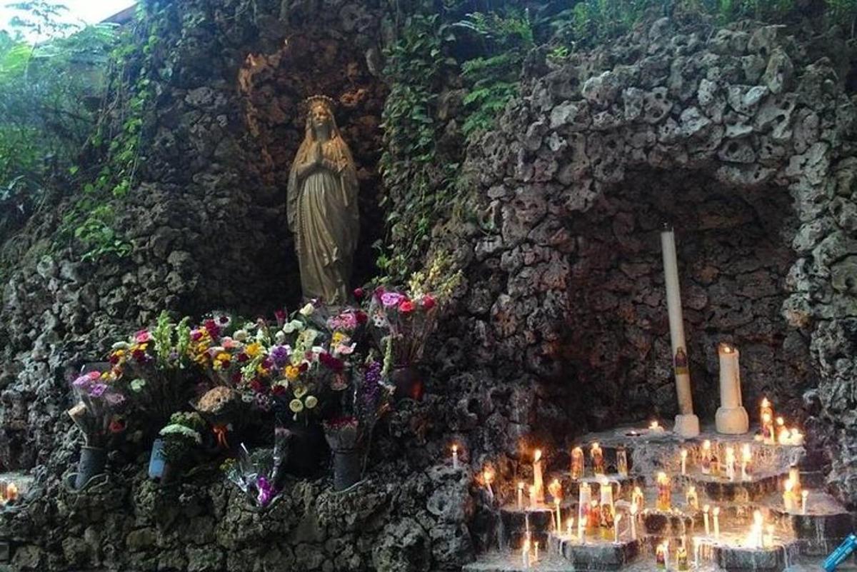 uma parede com uma estátua, flores e velas