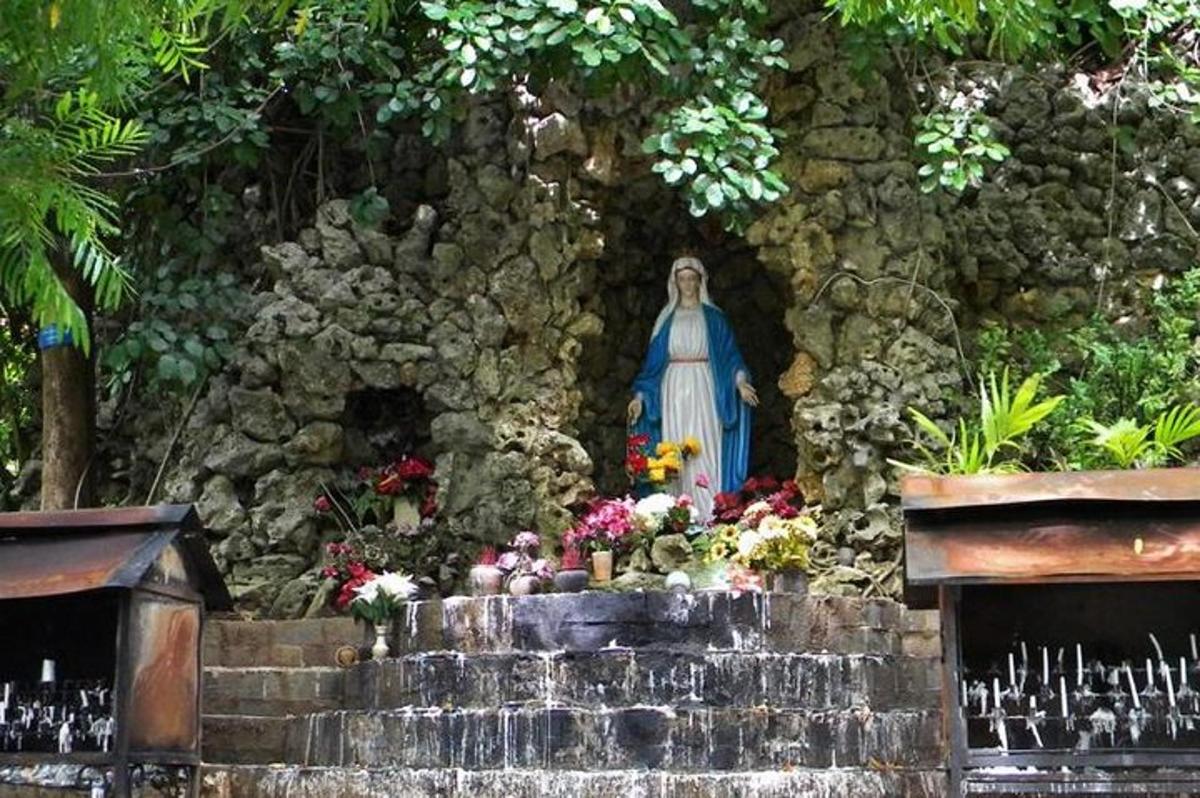 uma estátua de uma mulher em um jardim com flores