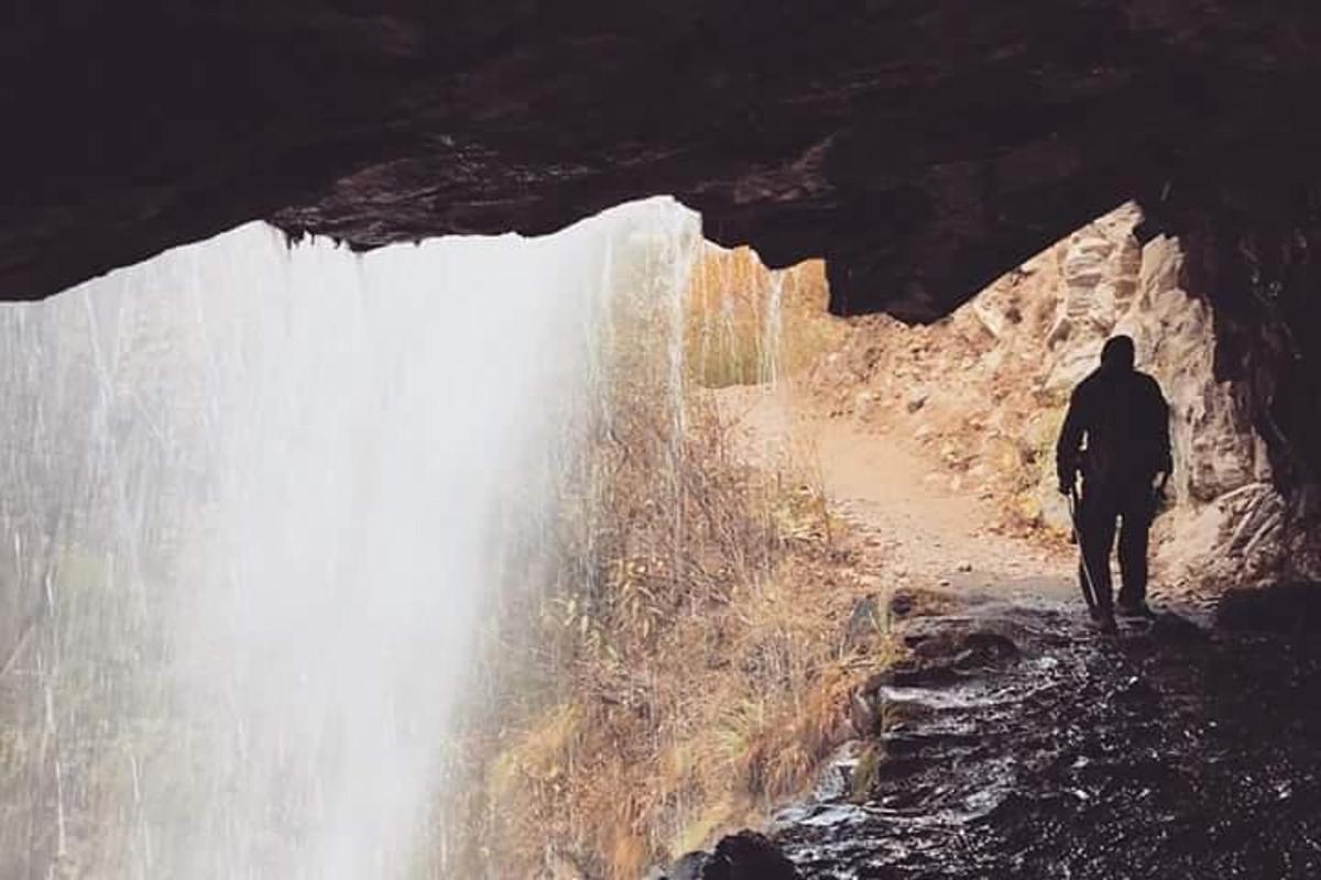 a man is walking in front of a waterfall