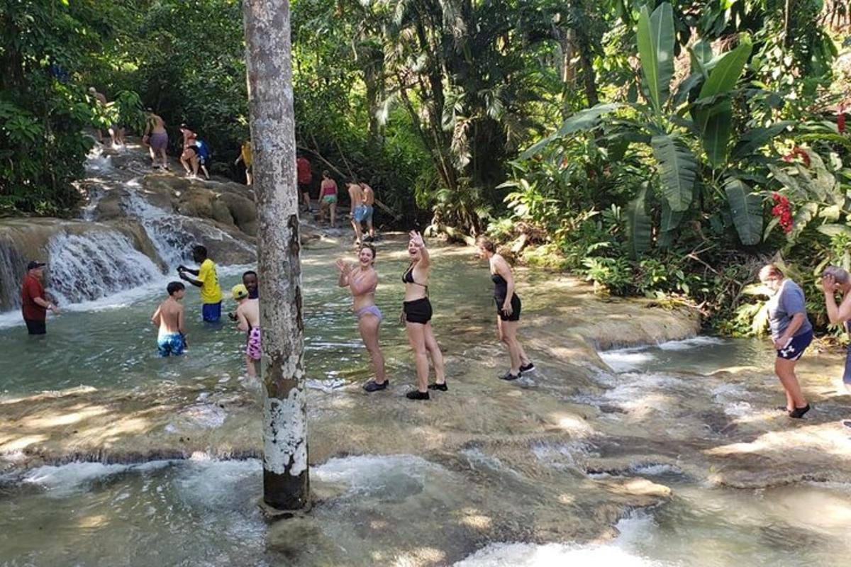 een groep mensen die in het water staan bij een waterval