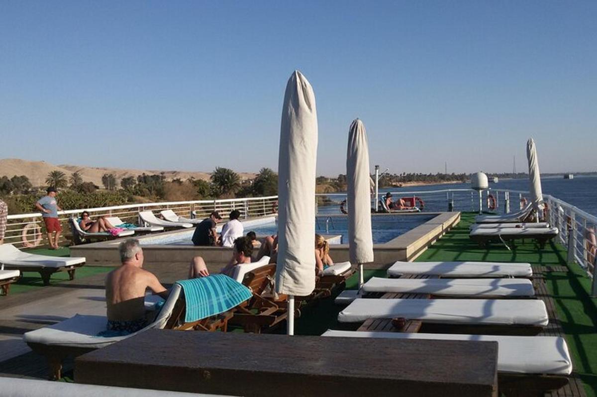 eine Gruppe von Menschen, die auf Liegestühlen neben dem Wasser sitzen
