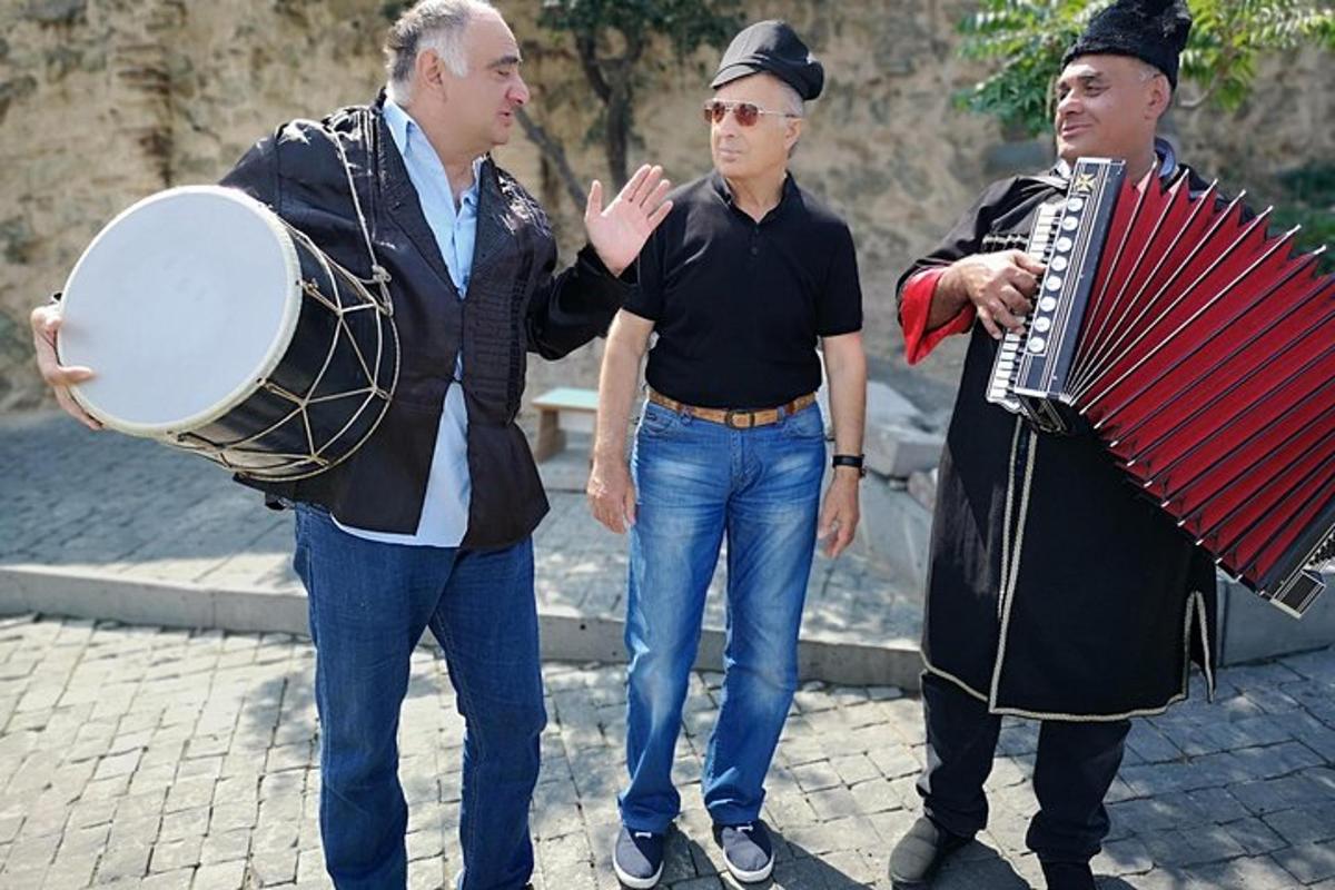 un gruppo di tre uomini in piedi su una strada con una fisarmonica