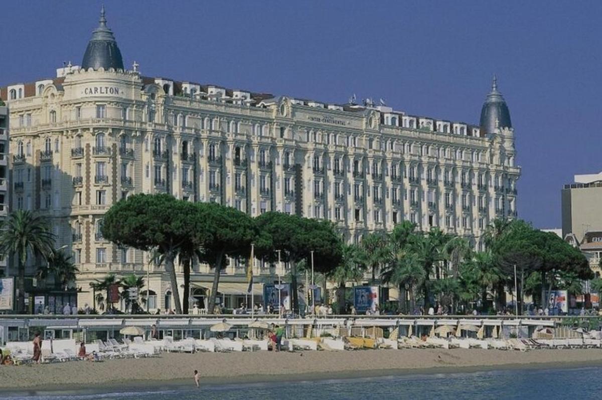 a large white building with trees in front of a beach