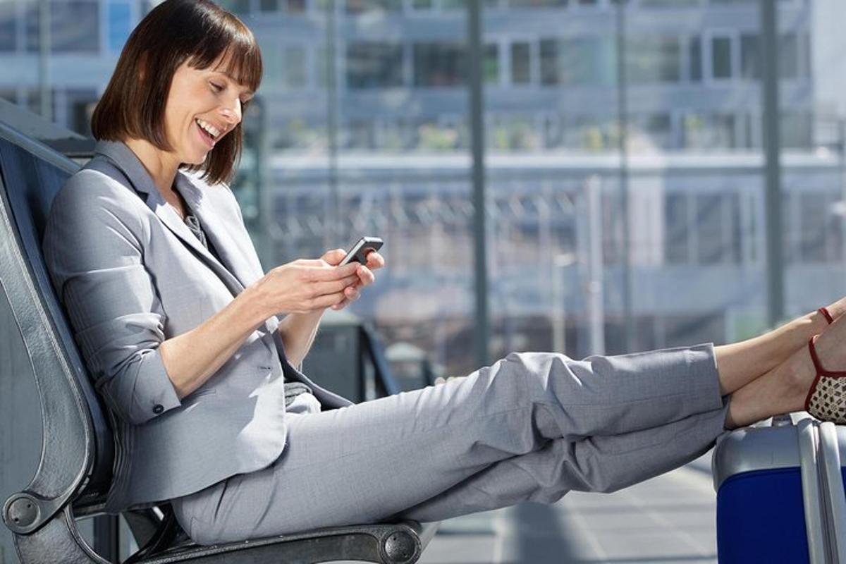 egy nő ül egy széken, és a mobiltelefonját nézi