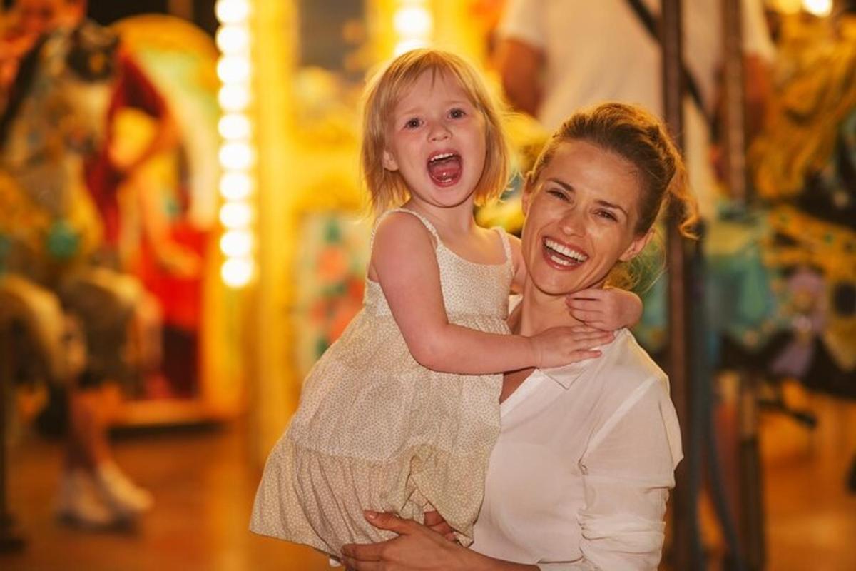 a woman holding a little girl on a carousel
