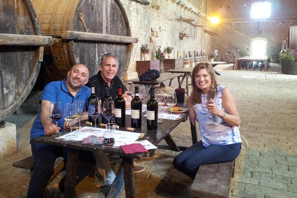 un gruppo di persone sedute a un tavolo con bottiglie di vino