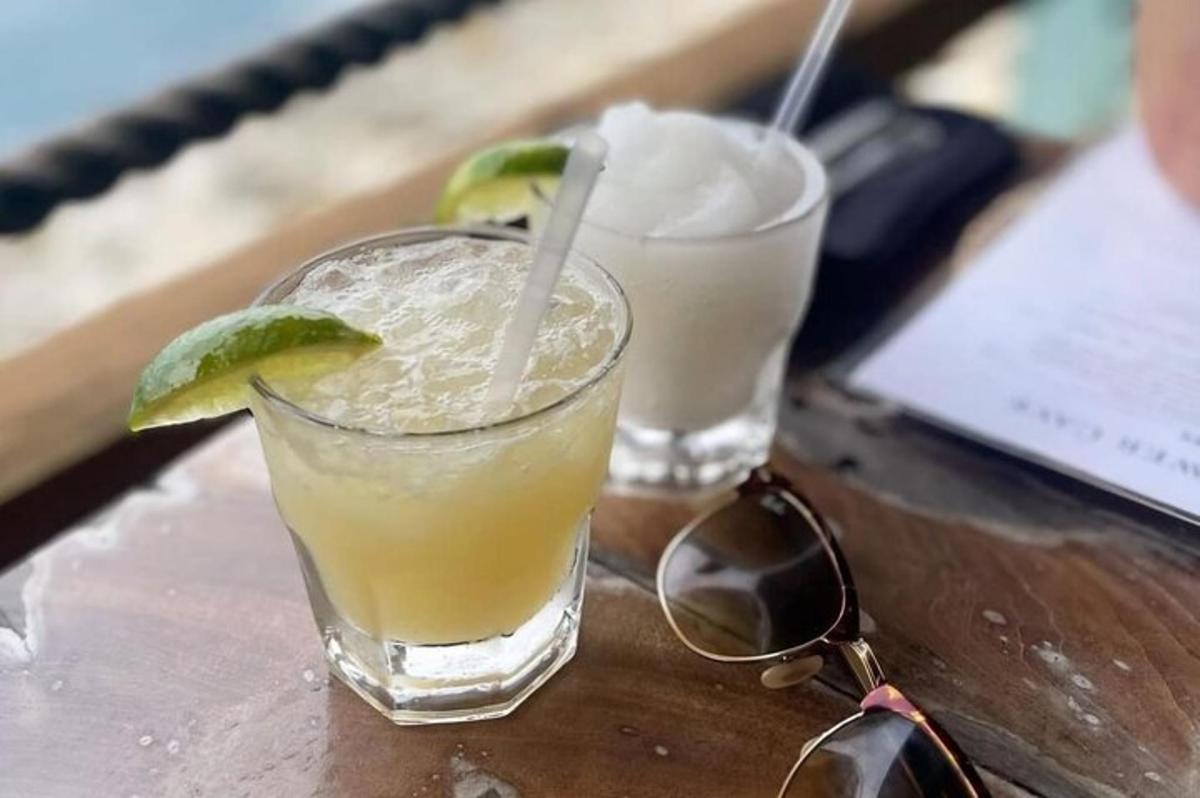 two drinks sitting on a wooden table with glasses