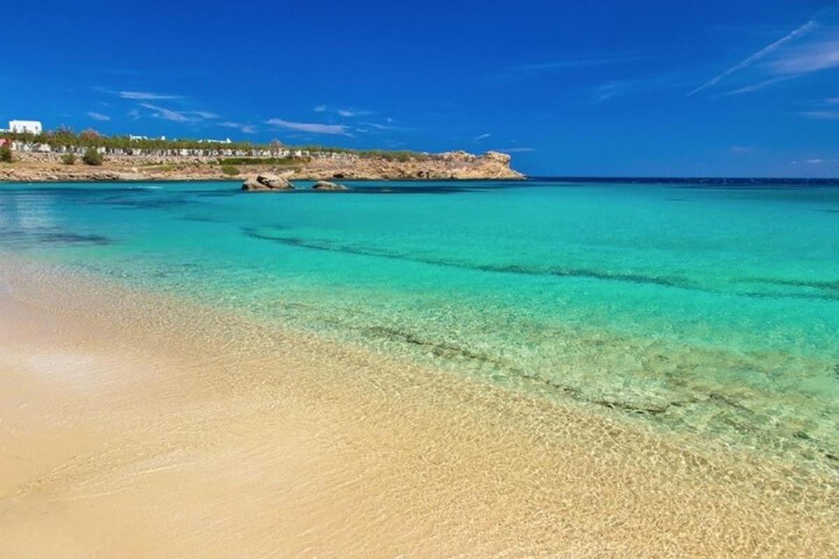 una spiaggia con acqua azzurra e cristallina e rocce sullo sfondo