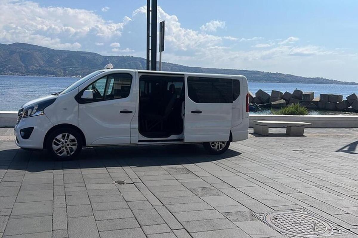 uma van branca estacionada ao lado de um corpo d'água
