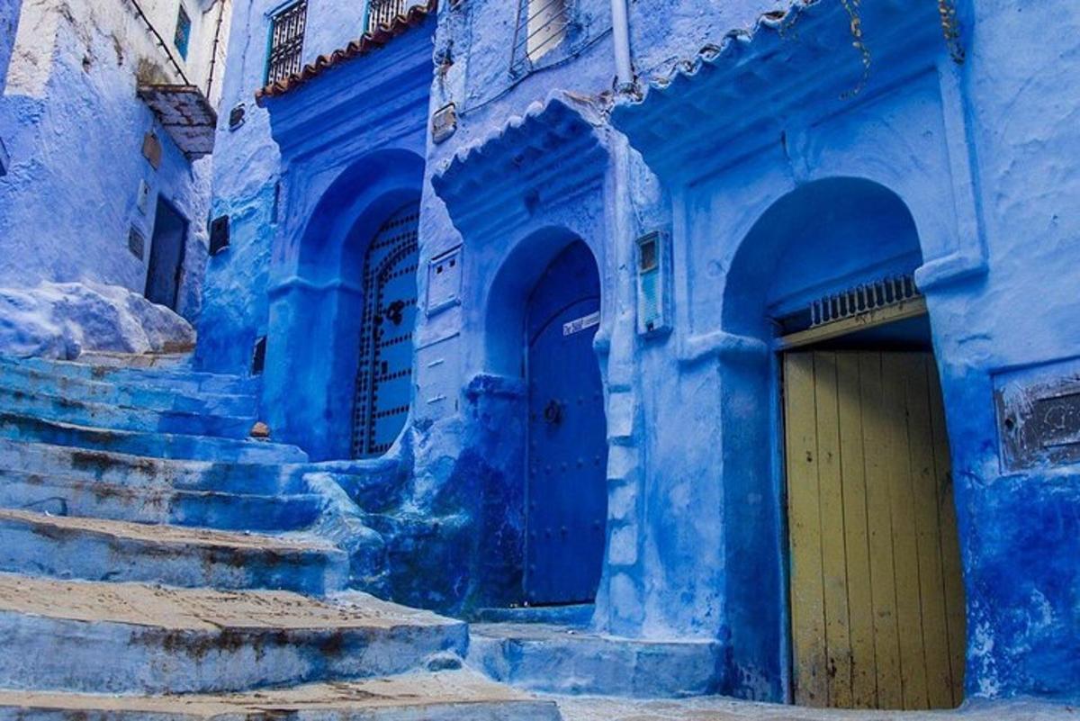 un edifici blau amb escales i una porta groga