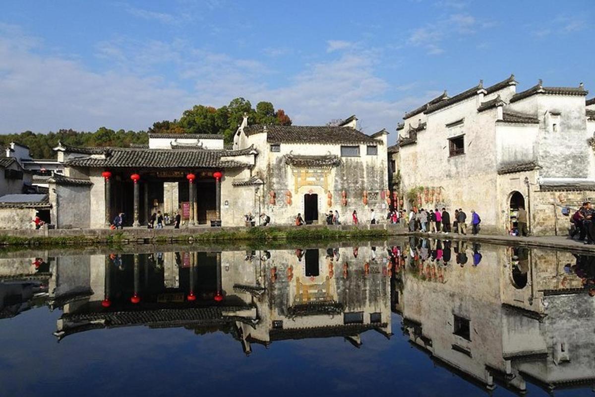 a group of people standing in front of buildings next to a lake