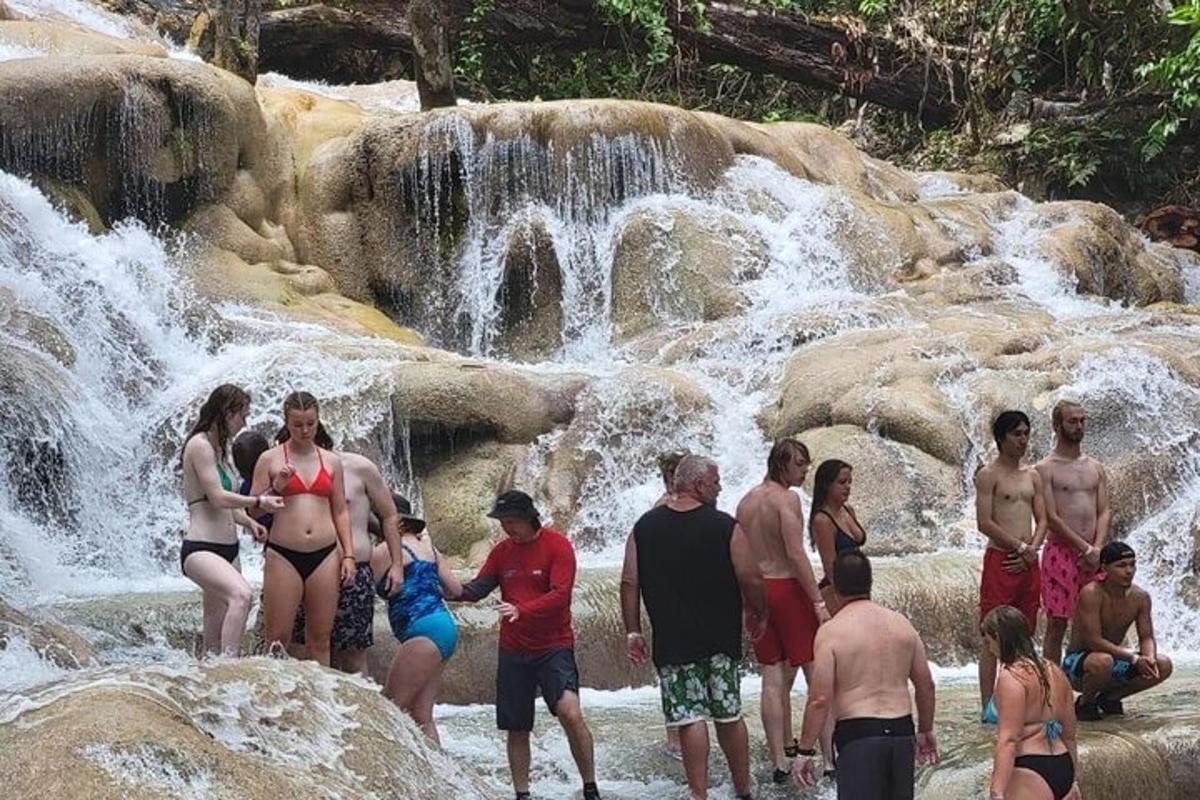 Un grupo de personas de pie frente a una cascada.