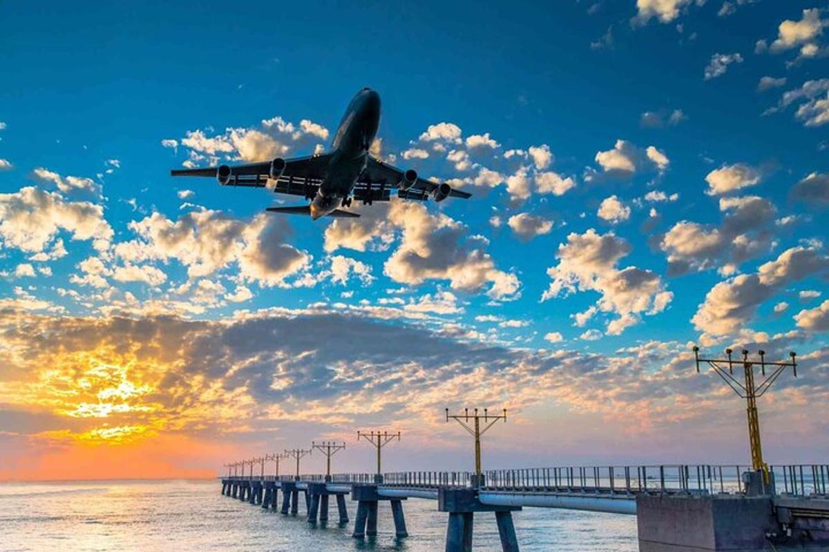 un aereo sta volando sopra un molo con l'oceano