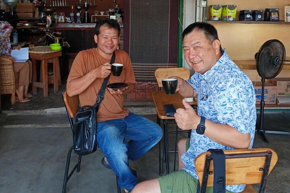 two men sitting in chairs with cups of coffee