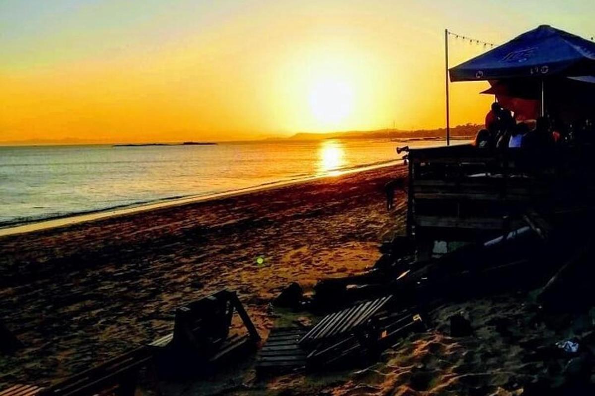en strand med en parasoll og stoler på stranden