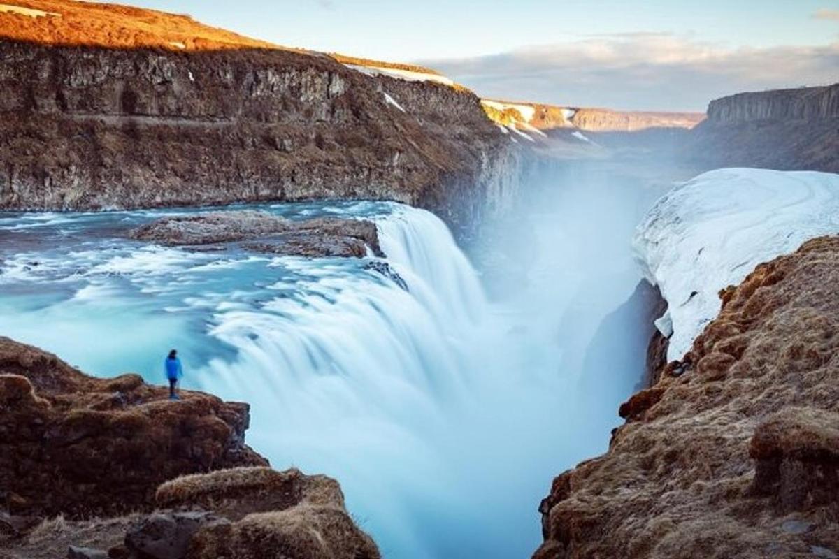 un uomo in piedi su una scogliera accanto a una cascata