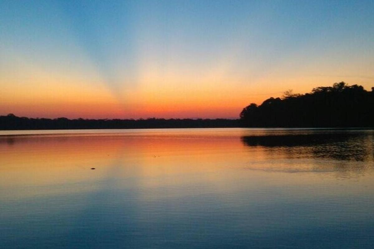 a sunset over a lake with a rainbow in the sky