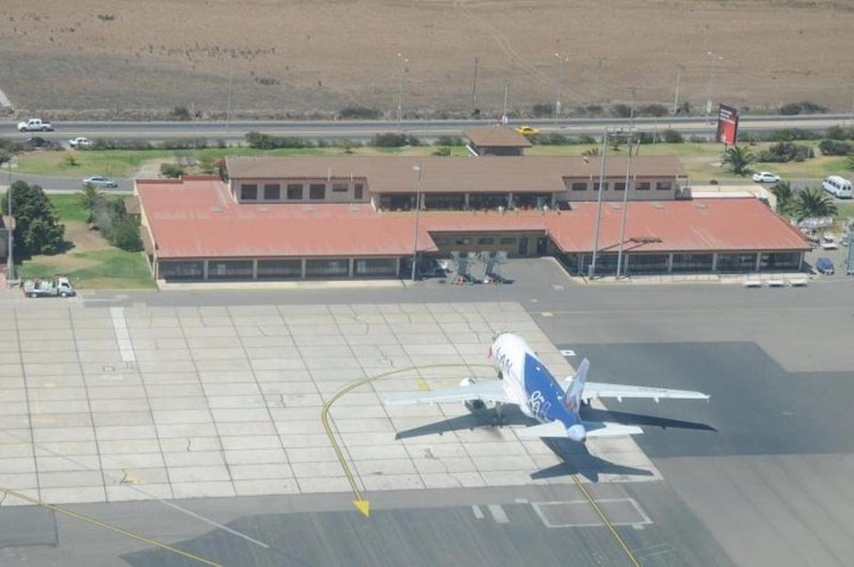 a blue and white airplane sitting on an airport runway